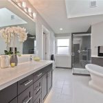 Master bathroom with dark wood vanity, arctic white quartz countertop and  freestanding tub
