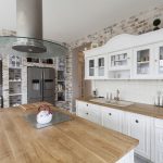 Solid surface countertops and modular Swedish cabinets freshen the look of  this European farmhouse. Task lighting is provided by metal industrial  pendants.