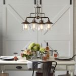 A rustic chandelier with vintage light bulbs over a table in a dining room.