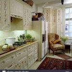 Armchair chair and folding screen beside large refrigerator town kitchen  with stencilled cream units