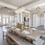 Light rustic dining room table with bench seating in large dining rooms  space. Long chandelier