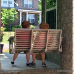 Children making memories on front porch swing